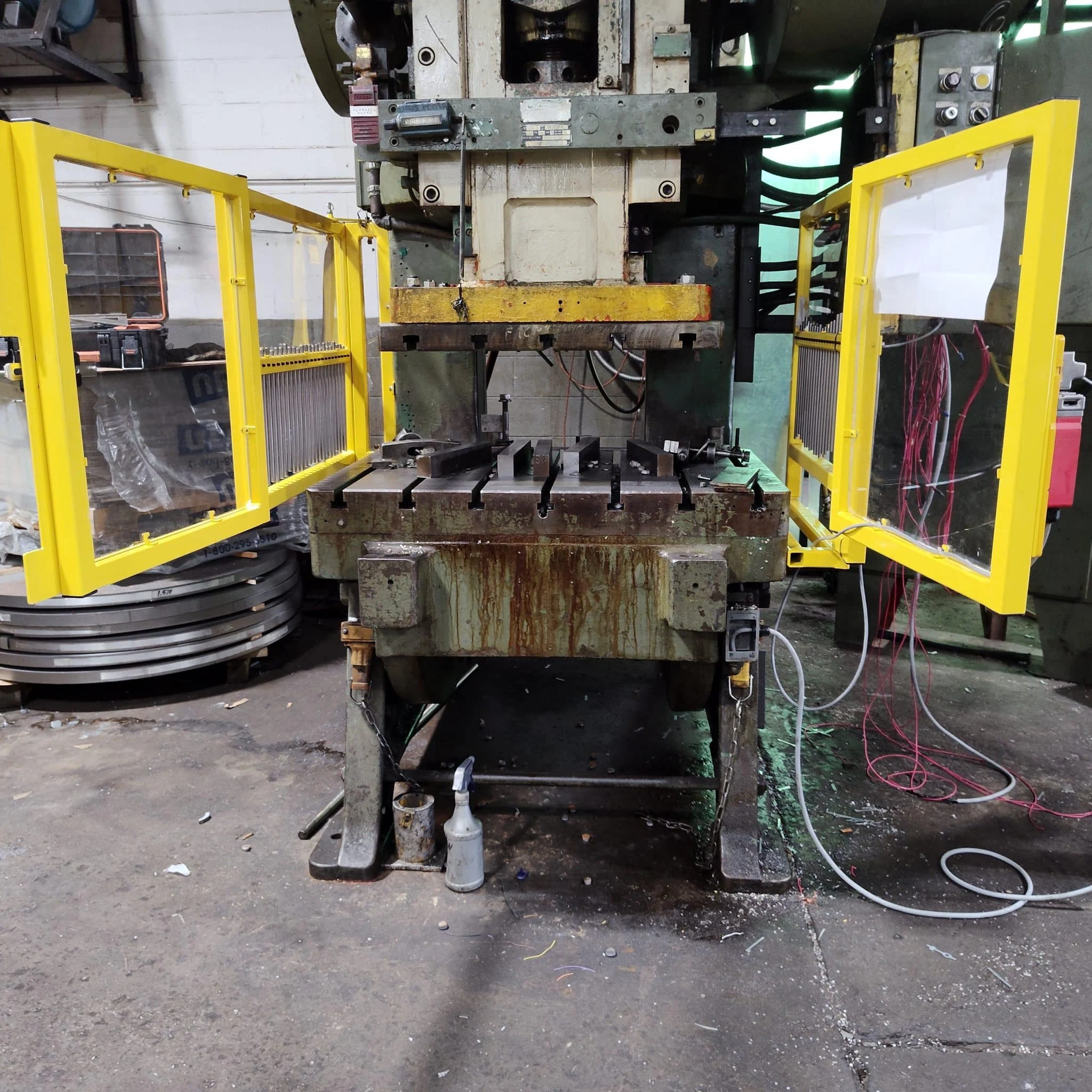 Yellow steel mesh machine guard with safety interlock on a press